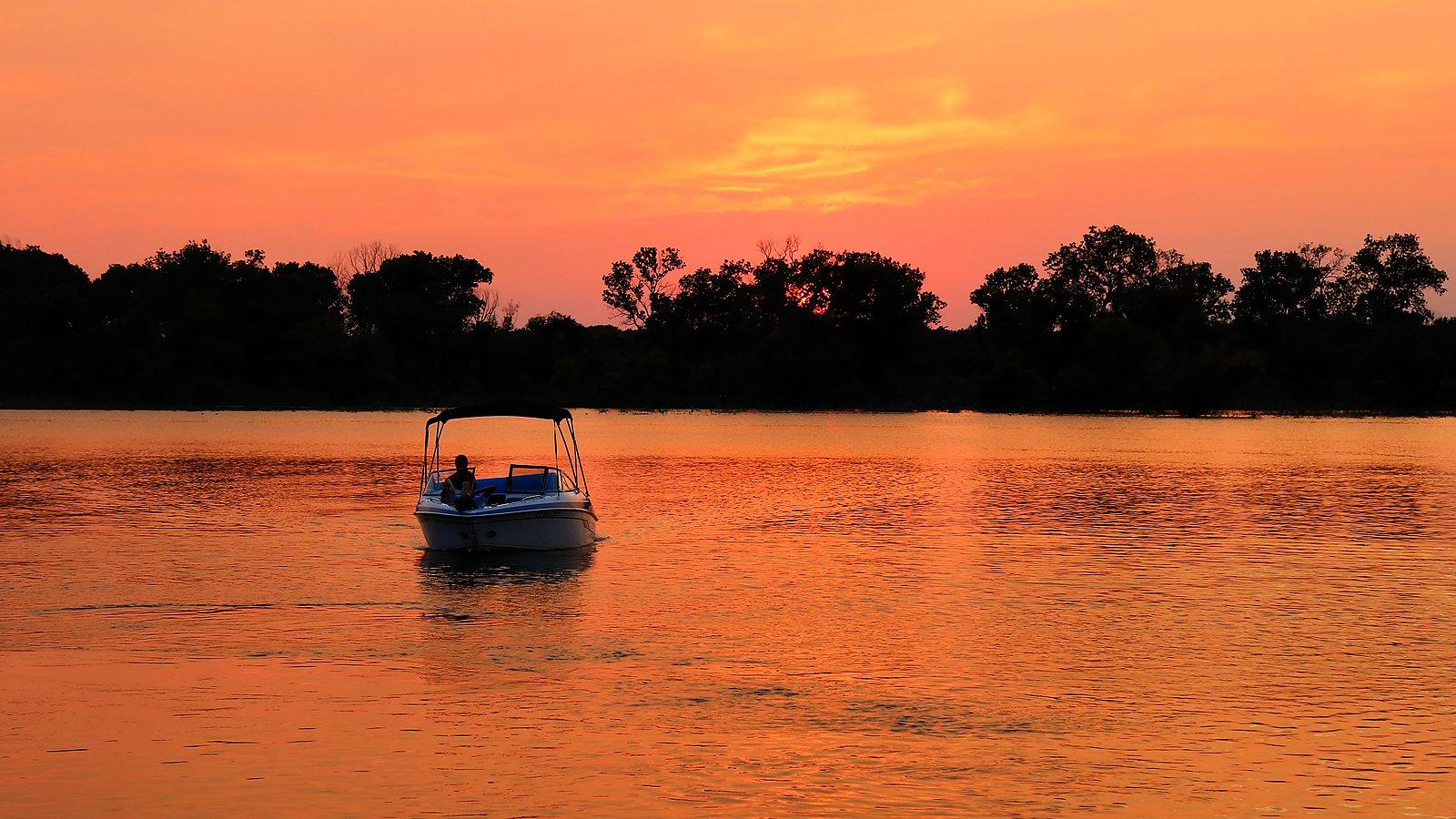 Orange sunset over Lake Whitney with a boat on the water
